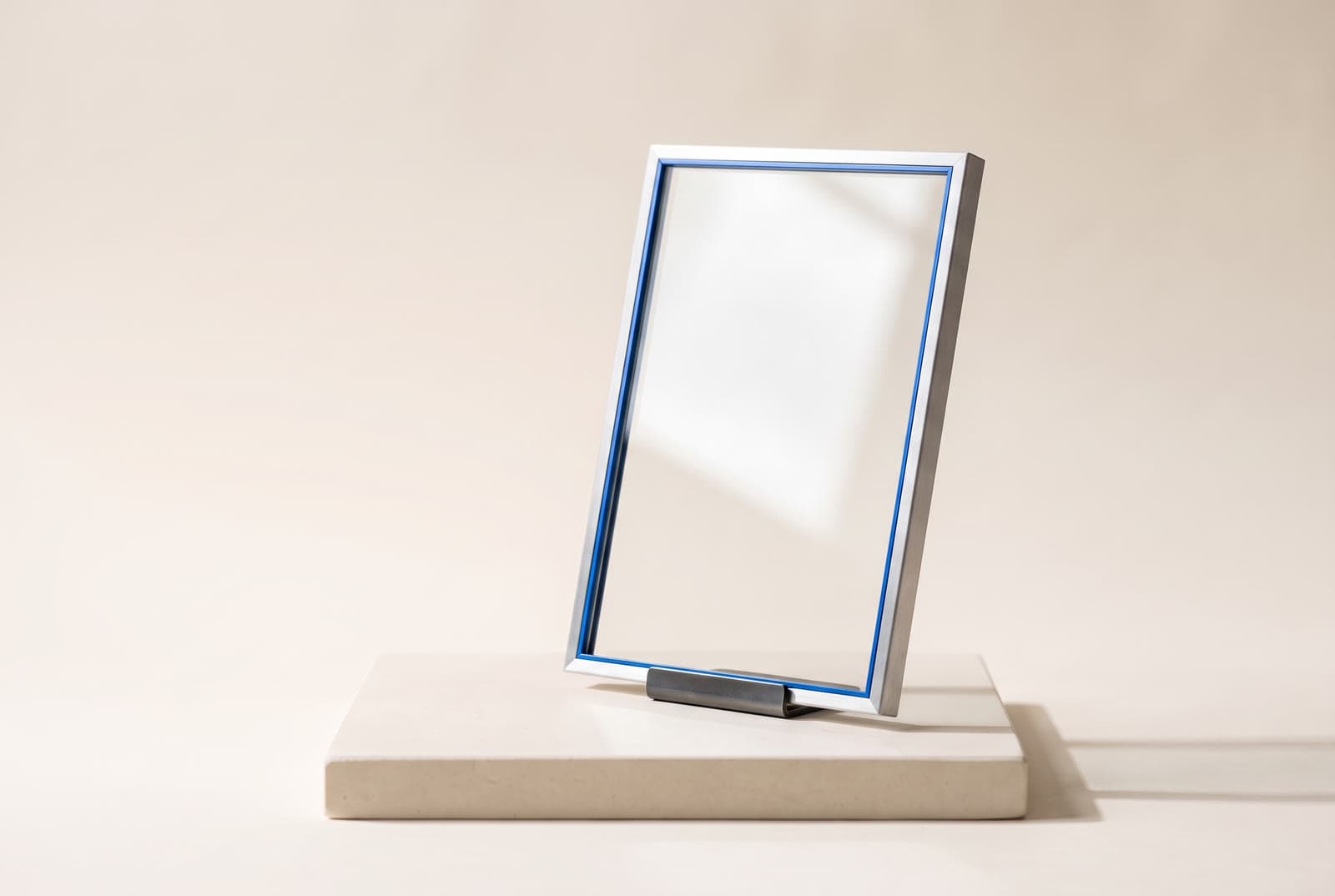 An upright pane of glass in a slim aluminium frame catching soft light