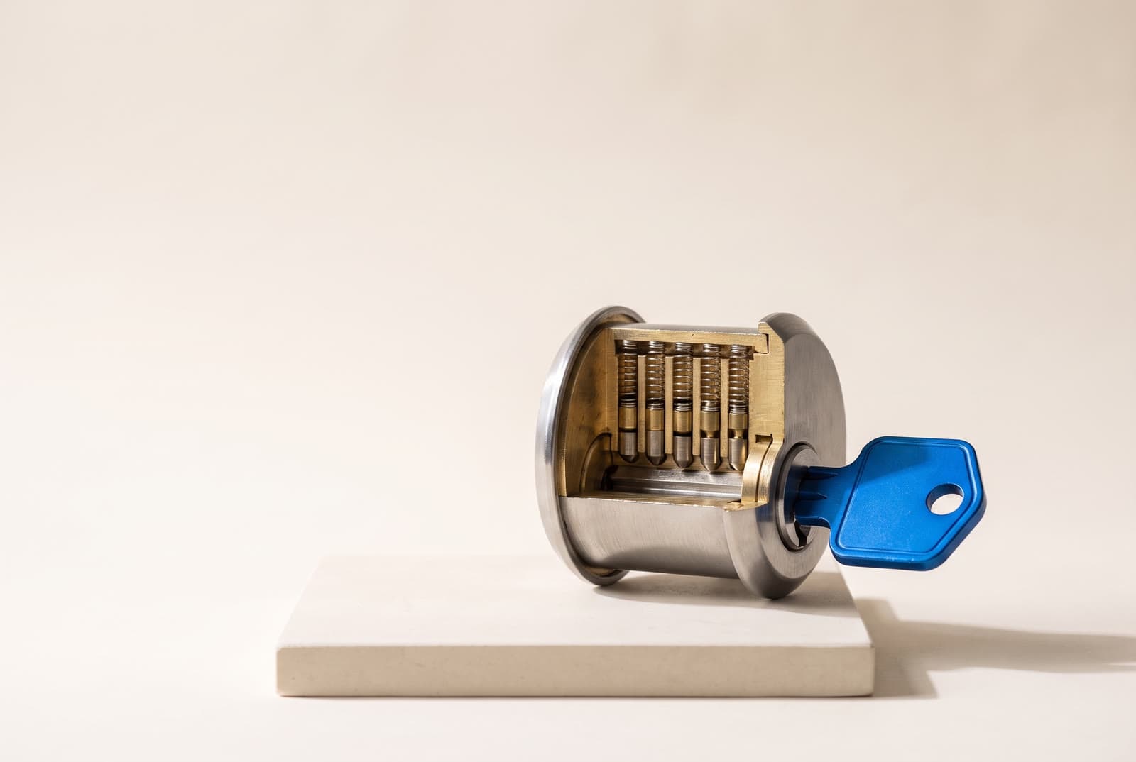A cutaway pin-tumbler lock cylinder with its pins aligned and a cobalt key inserted